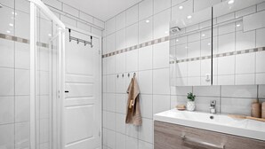Un bagno moderno con doccia, lavandino con specchio e porta asciugamani.