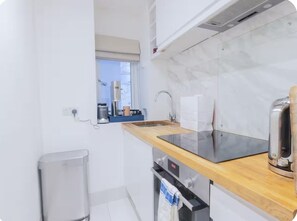 A compact kitchen with a wooden countertop, stainless steel appliances, and a window. - Chic 1 bedroom flat in Cadogan Square with terrace (London)