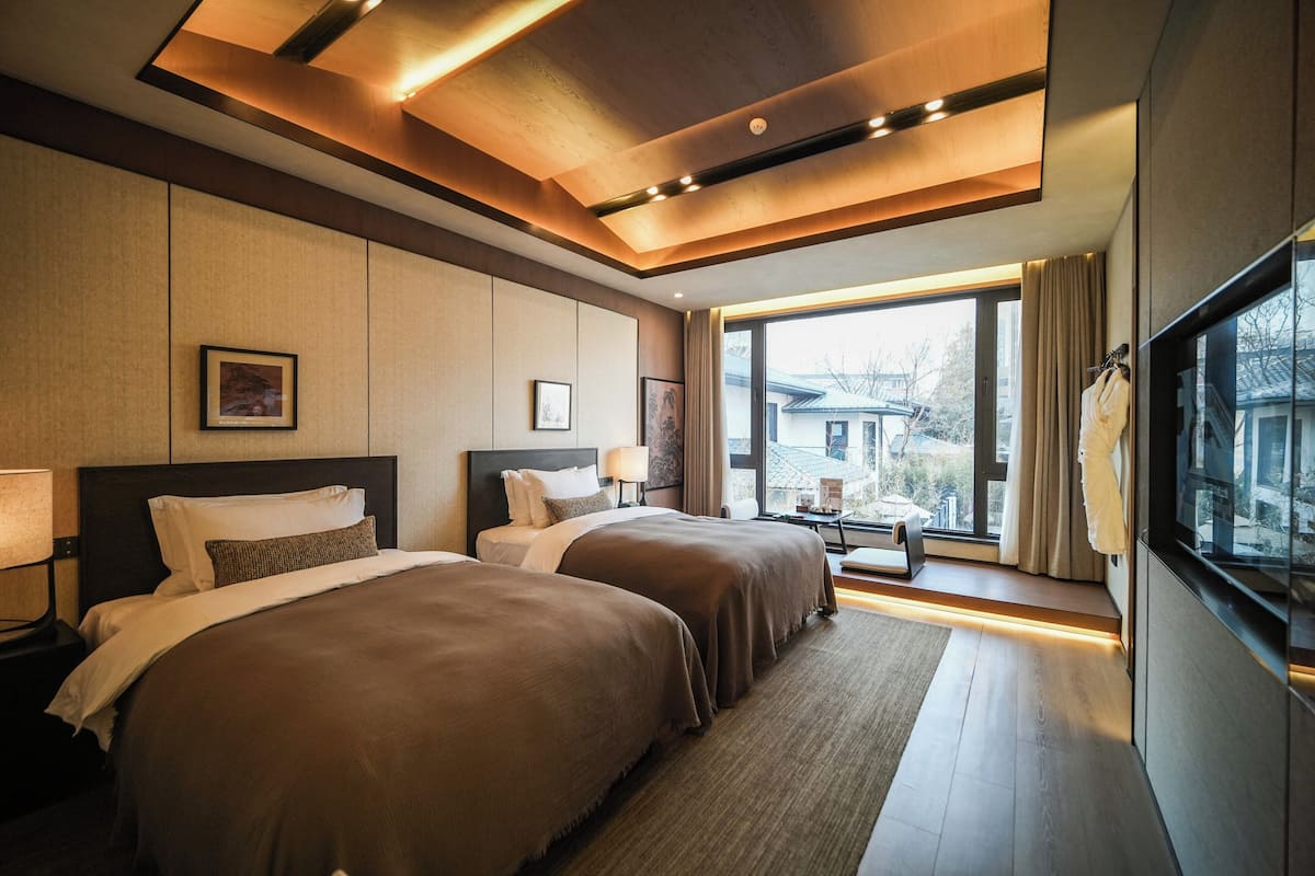 Une chambre d’hôtel avec deux lits, une grande fenêtre et une vue sur la ville.