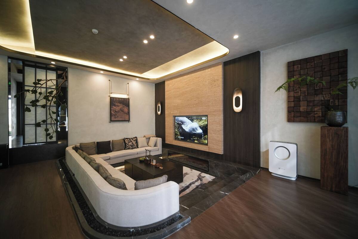 Un salon moderne comprenant un canapé d’angle, un téléviseur à écran plat, une table basse et une cheminée intégrée.