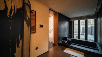 A modern interior with a wooden floor, a large window, and a door leading to another room.