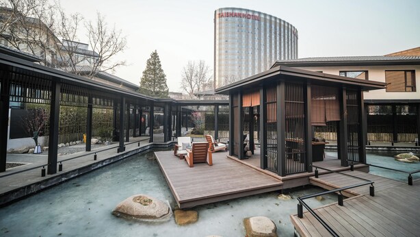 A courtyard with a pool, wooden deck, and seating area.