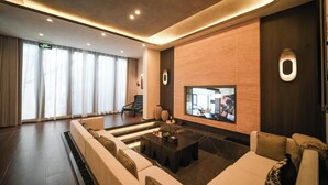 A modern hotel lobby with a seating area, a flat-screen TV, and a wooden accent wall.