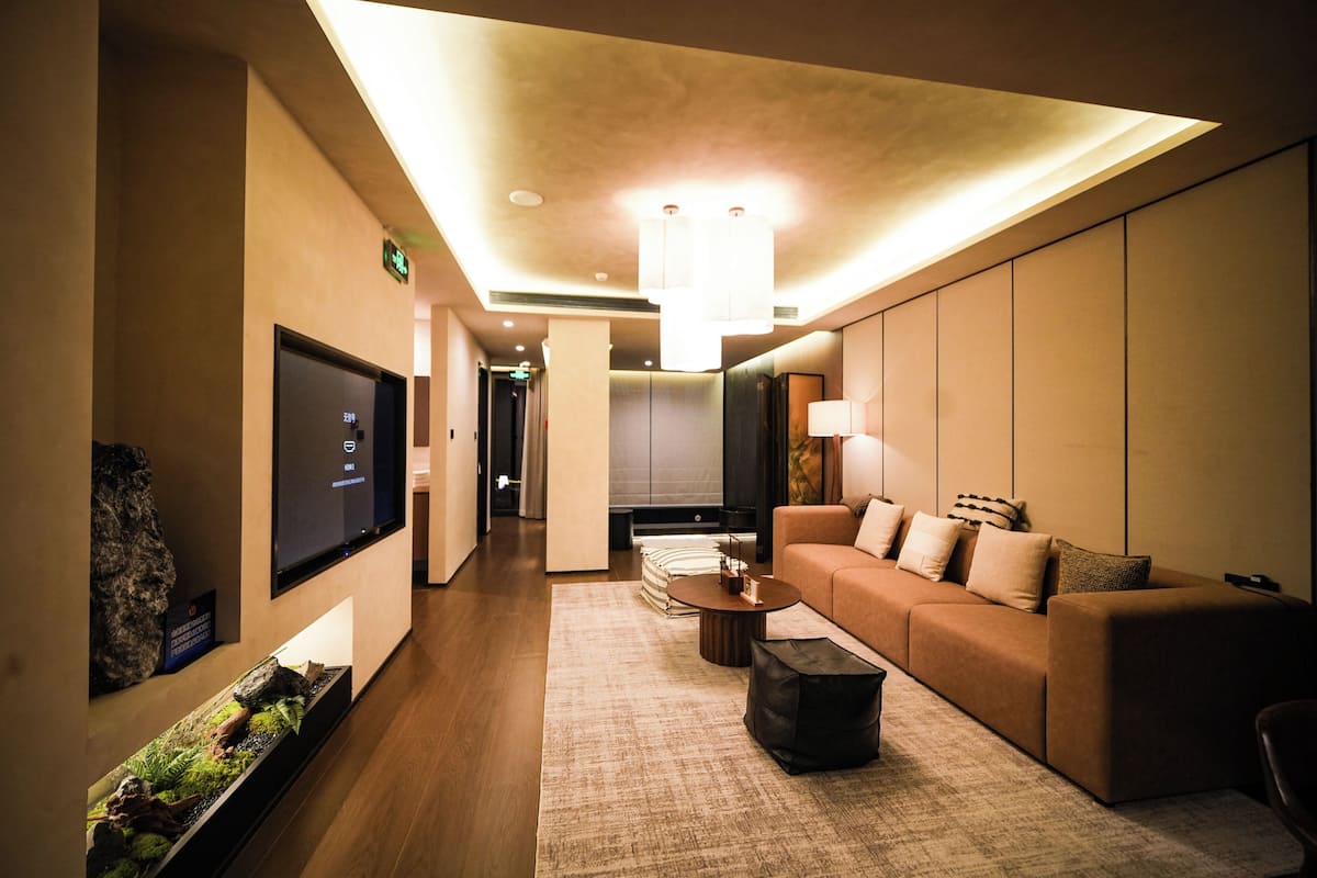 Une chambre d’hôtel moderne équipée d’un téléviseur à écran plat, d’un canapé, d’une table basse et agrémentée d’un petit jardin décoratif avec des rochers.