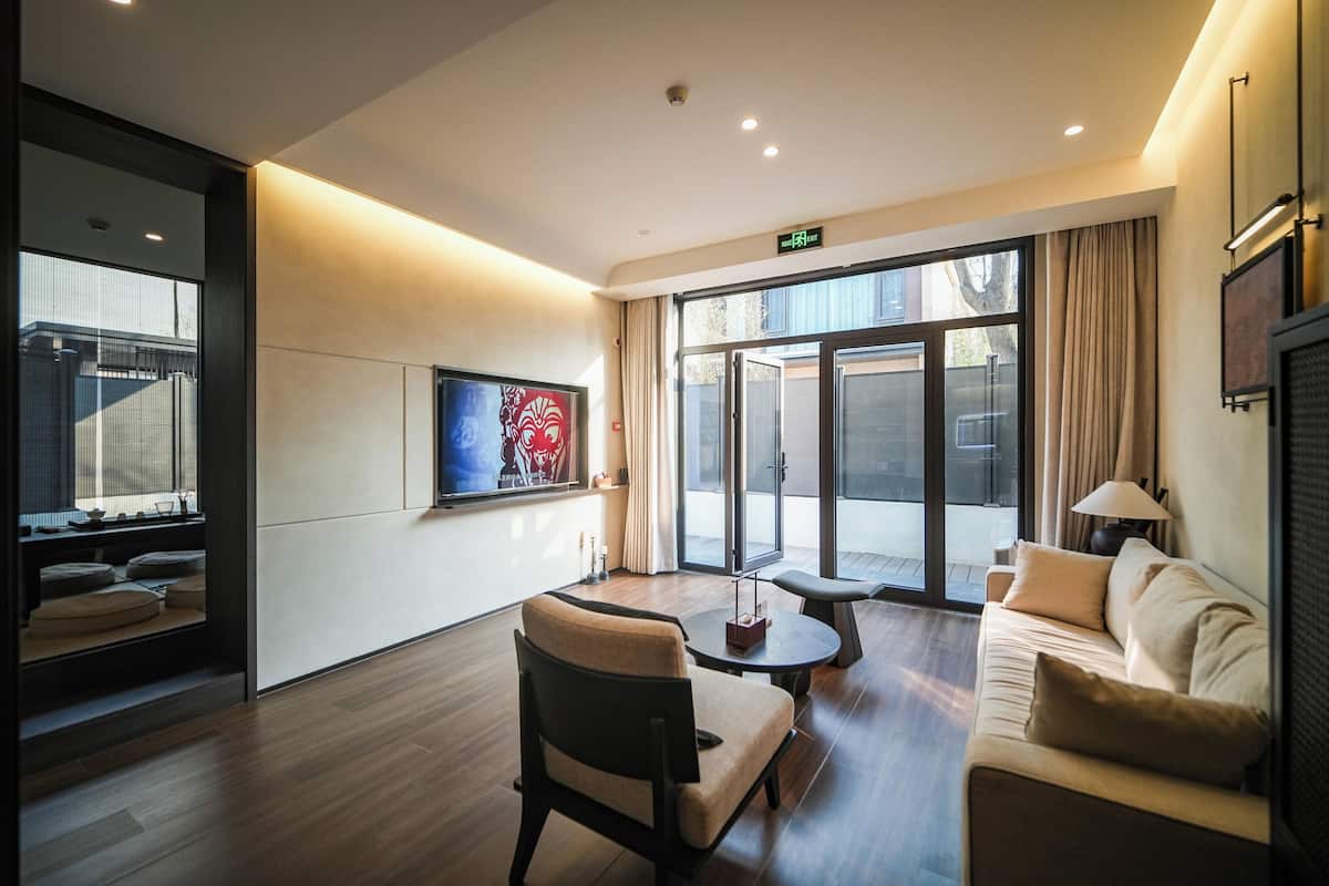 Un hall d’hôtel moderne avec un canapé, un fauteuil et un téléviseur fixé au mur.