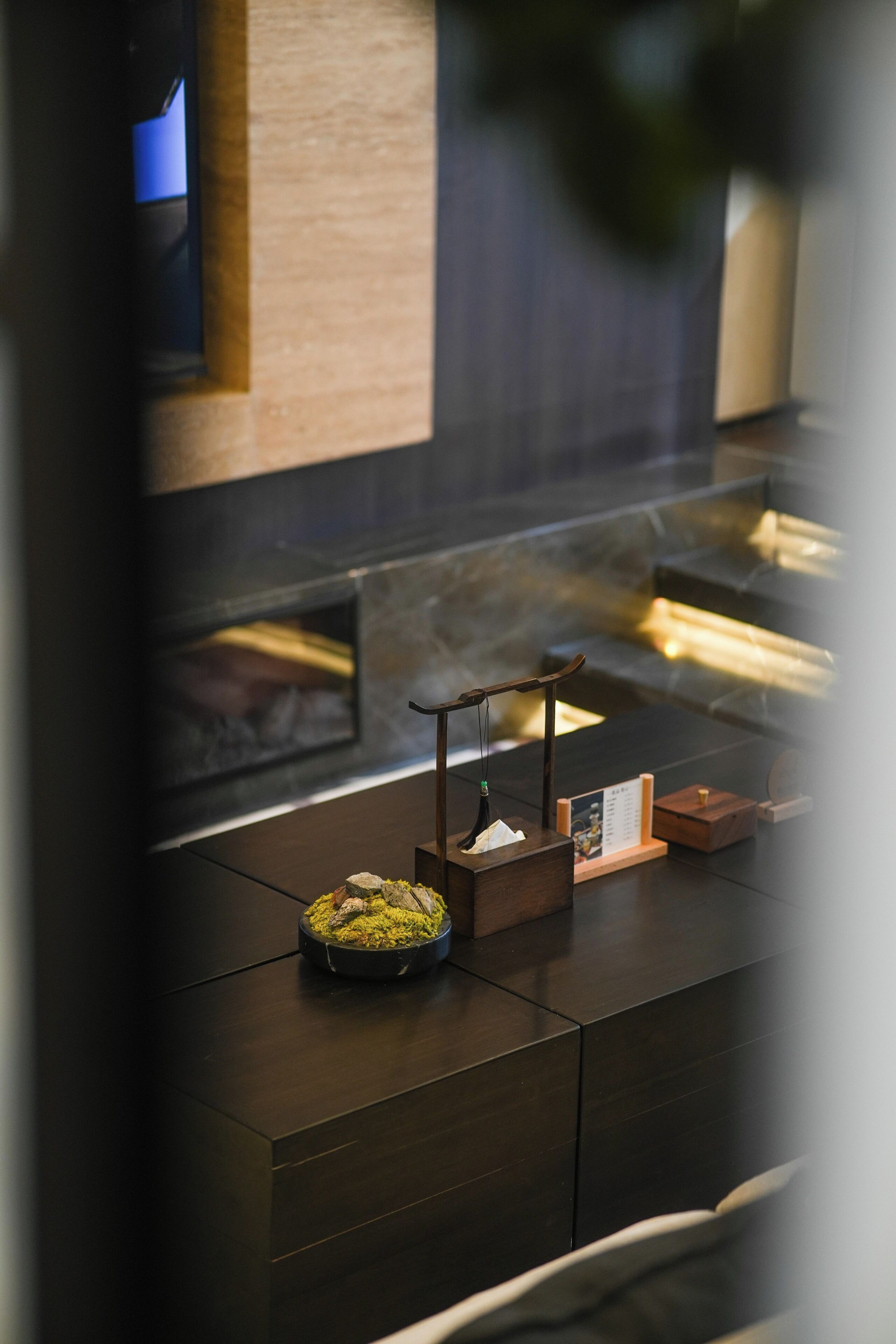 A modern kitchen with a built-in oven, a wooden cabinet, and a small table with a bowl of green substance.