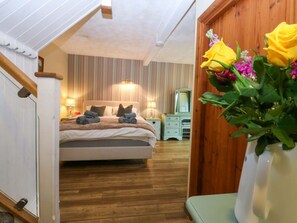 A bedroom with a bed, bedside tables, a dresser, and a wooden staircase. - Hafod, Ty Mawr Farm in Llanddeiniolen (Caernarfon)