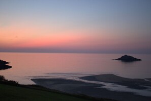 A coastal landscape with a body of water, a small island, and a distant shoreline. - Langurra in Crantock, Cornwall (Newquay)