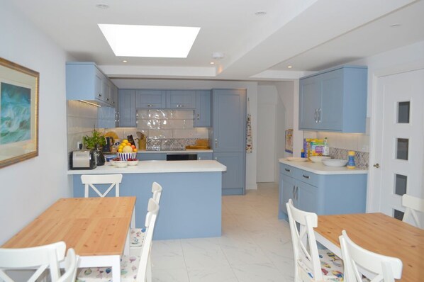 A modern kitchen with blue cabinets, a central island, and white chairs.