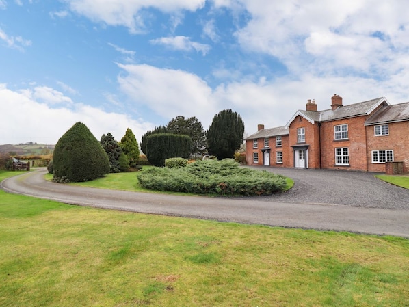 A large brick building with a driveway and well-maintained lawn.