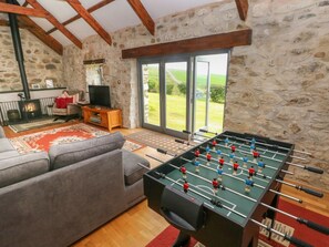 A cozy room with a foosball table, a sofa, a fireplace, and a stone wall. - Bryn Nante, Maenclochog, Wales (Clynderwen)