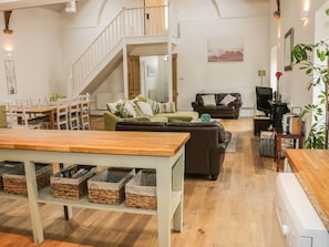 Un grand espace de vie comprenant une table à manger, des canapés, un escalier et un téléviseur.