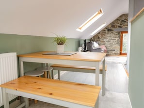 A kitchen with a wooden table, a potted plant, and a stone wall.
