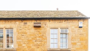 Un bâtiment en pierre avec une porte verte, portant le numéro 20, et deux fenêtres à l’étage supérieur.