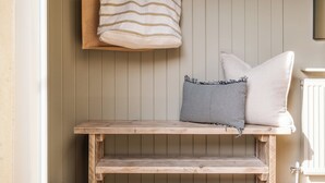 Un banc en bois avec des coussins, un sac suspendu et un radiateur.