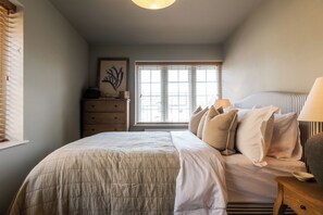 A bedroom with a bed, bedside table, lamp, dresser, window, and artwork. - Beautiful 2 BD Home in The Cotswolds (Moreton-in-Marsh)