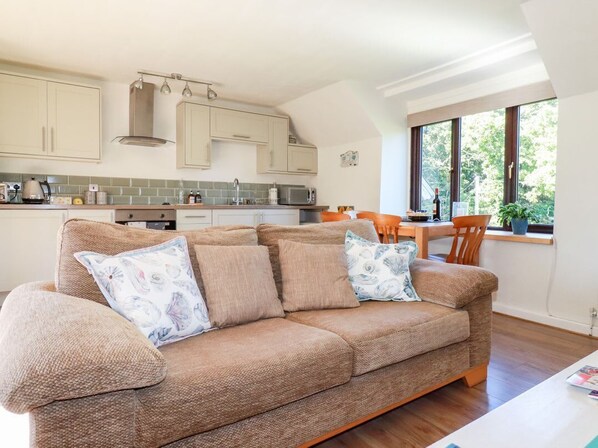A cozy living room with a sofa, a dining table, and a kitchen area with cabinets and appliances.