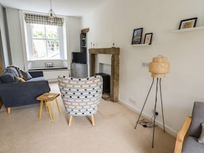 Un salon comprenant un canapé, un fauteuil à motifs, une cheminée, un lampadaire et une fenêtre donnant sur un beau paysage.
