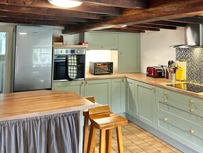 A kitchen with a wooden table, stools, a refrigerator, oven, microwave, and a toaster. - Broadhay, Hathersage (Hope Valley)