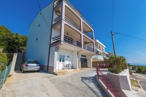 A multi-story building with a car parked in front, a staircase, and a view of the sea. - Cozy studio for 2, terrace with sea view (Crikvenica)
