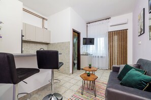 A compact living space with a kitchenette, a sofa, a small table, and a TV. - Cozy studio for 2, terrace with sea view (Crikvenica)