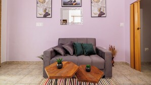 Una sala de estar con un sofá gris, dos mesas de centro de madera y tres cuadros enmarcados en la pared.