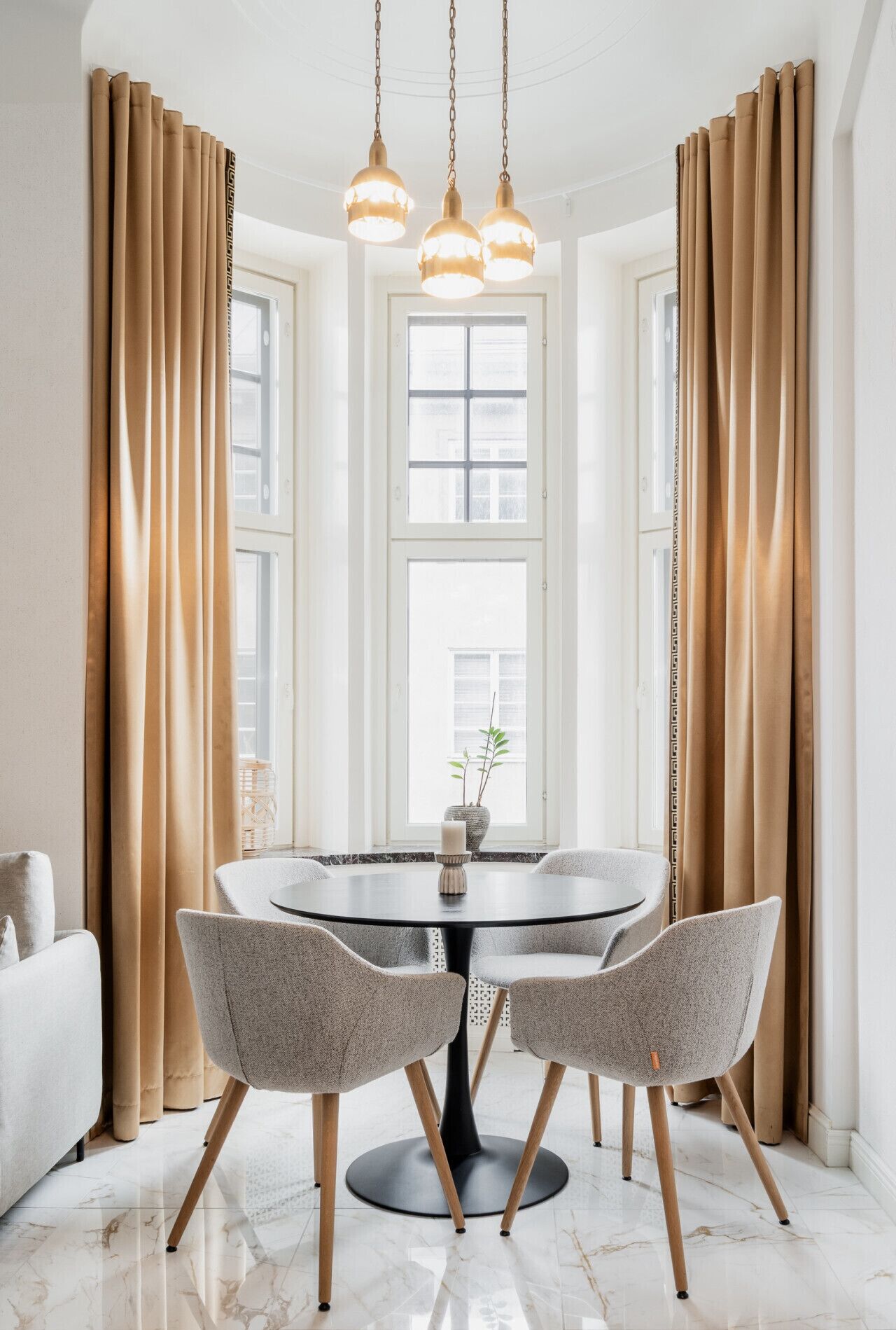 A dining area with a round table, two chairs, and a hanging light fixture.