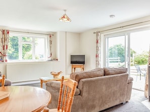 A living room with a sofa, a television, a dining table, and a chair. - Charming Foxlair Cottage Retreat (Minehead)