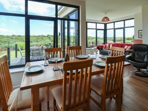 A dining area with a table set for six, large windows, and a view of greenery. - 29 Gap Road, Hunmanby (Filey)