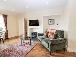 Ein Wohnzimmer mit einer Couch, einem Fernseher, einem Kamin und einem gemusterten Teppich.