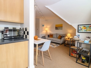 A compact living space with a kitchenette, a dining area, a sofa, and a small table with a lamp.