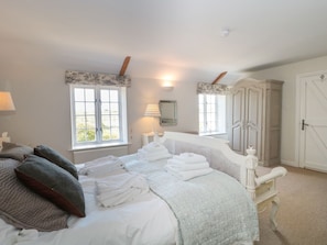 Ein Schlafzimmer mit Bett, Fenster, Lampe, Kleiderschrank und Tür.