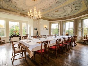 A formal dining room with a long table set for a meal, surrounded by wooden chairs with red cushions. - Caynham Court, Caynham, Ludlow (Ludlow)