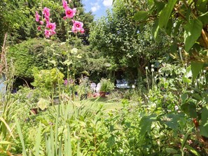 A garden with various plants and flowers, a pathway, and a seating area with chairs. - Turnpike Lodge, Brixham, Devon. (Paignton)