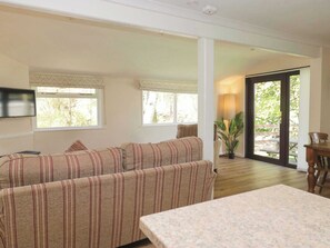 A living room with a sofa, a TV, and a dining table.