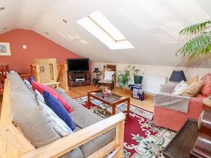 A living room with a sofa, a coffee table, a TV, and a red wall. - Berry Barn, Mablethorpe (Alford)