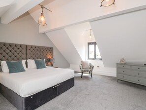 Ein Schlafzimmer mit einem großen Bett, einem Sessel, einem Schminktisch und einem Fenster.