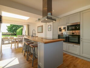 Eine moderne Küche mit einer zentralen Kochinsel, Barhocker und eingebauten Geräten.
