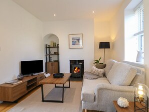 Ein Wohnzimmer mit Kamin, einer Couch, einem Fernseher und einem Bücherregal.