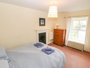 A bedroom with a bed, a dresser, a radiator, and a window.