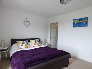 Un dormitori amb un llit, una decoració amb forma de cor, una taula petita i un quadre al mur.