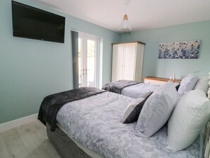 Ein Schlafzimmer mit zwei Betten, einem Kleiderschrank, einem Fernseher und einem Bild an der Wand.