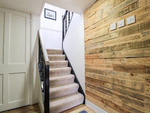 A staircase with carpeted steps and a wooden wall with light switches. - Beech Cottage, Stornoway (Isle of Lewis)