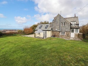 A house with a large lawn, a detached garage, and a view of the sea.