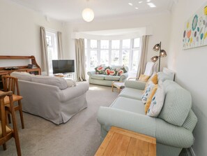 A living room with a sofa, a chair, a coffee table, a TV, and a lamp. - Seawinds 2a, Rhos-On-Sea (Colwyn Bay)