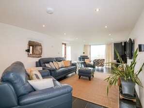 A spacious living room with a large sofa, a coffee table, and a television mounted on the wall. - Sleepy Fox, Blisland (Bodmin)