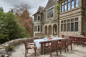 A stone building with a dining area featuring a table set for six, surrounded by chairs. - Oughtershaw Hall, Hawes (Skipton)