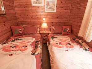 Una habitación acogedora estilo cabaña con dos camas, cada una decorada con ropa de cama temática navideña.