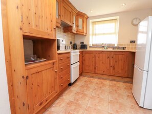 A kitchen with wooden cabinets, a white refrigerator, a microwave, and a toaster. - Garreg Wen Isaf Bach, Penygroes (Penygroes)