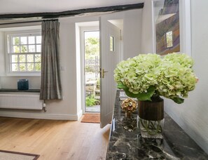 Habitació amb taulell de marbre, una planta en test, finestra amb cortines i porta que dona a l'exterior.